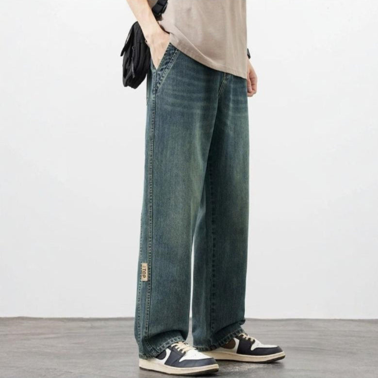 Person wearing blue jeans and black and white sneakers on a plain background
