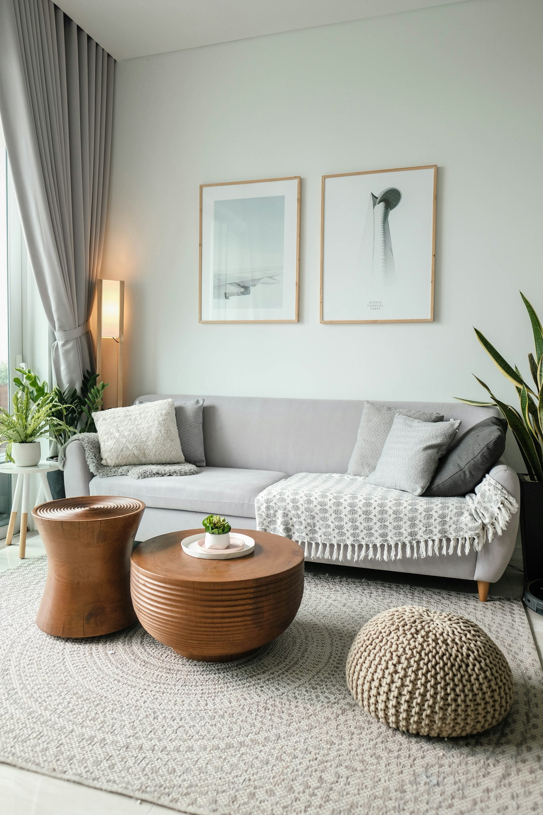 A neutral, sun-lit pile of folded natural-fibre garments resting on a wooden surface.